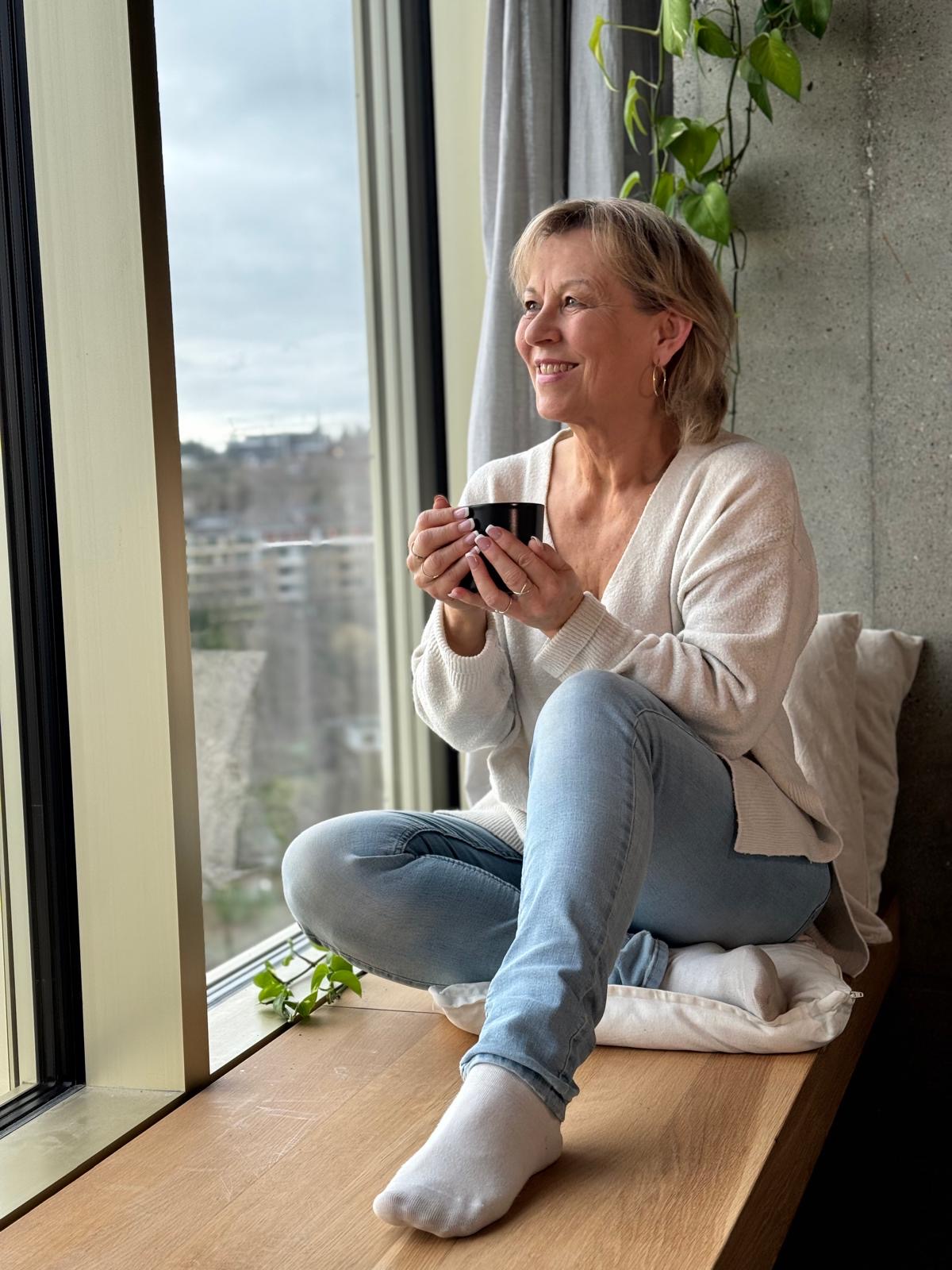 Martina Hannich sitzt mit einer Tasse Tee am Fenster